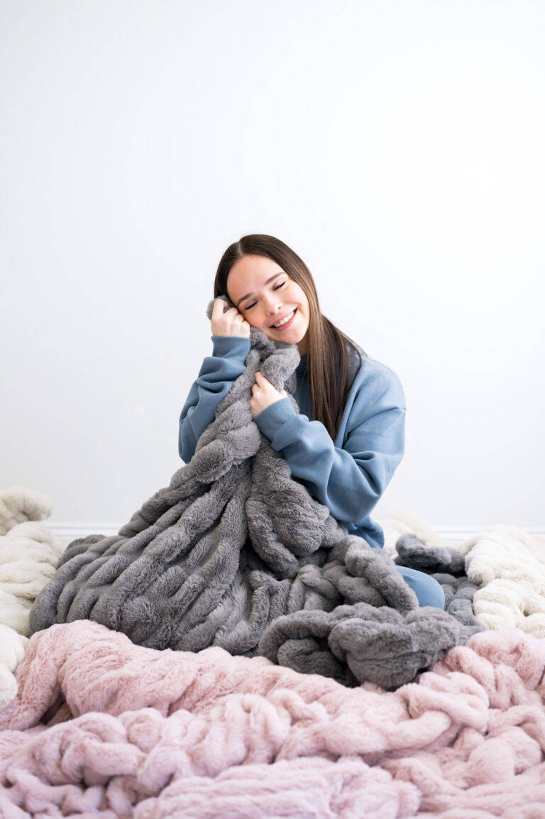 Woman snuggled with minky blanket and dressed in Comfrt sweatshirt